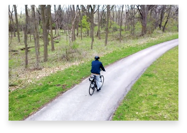 Retired man riding bike on a bike path near the woods.