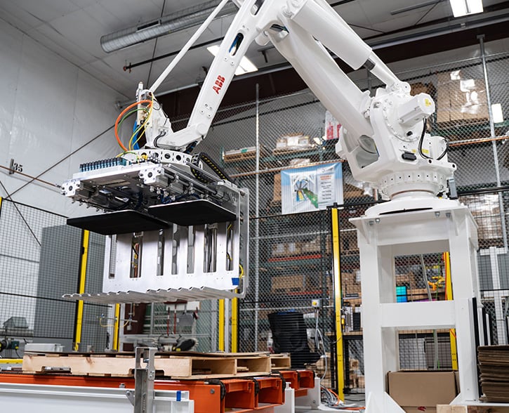 Large robot arm in a manufacturing plant carrying a piece of equipment.